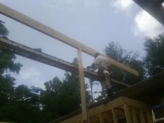 Carpenter setting a ridge beam over a new addition frame — Ice Dam Removal by Roofing Brothers in Athol