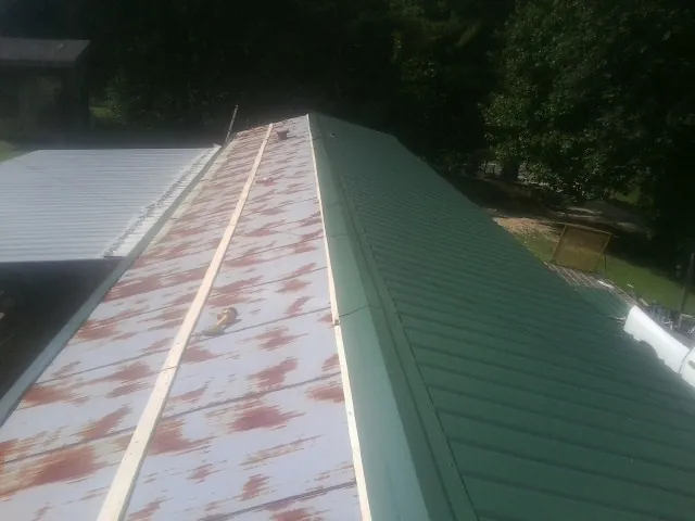 Old rusted panels beside newly installed green metal roofing — Wind Damage Roof Repair by Roofing Brothers in Athol
