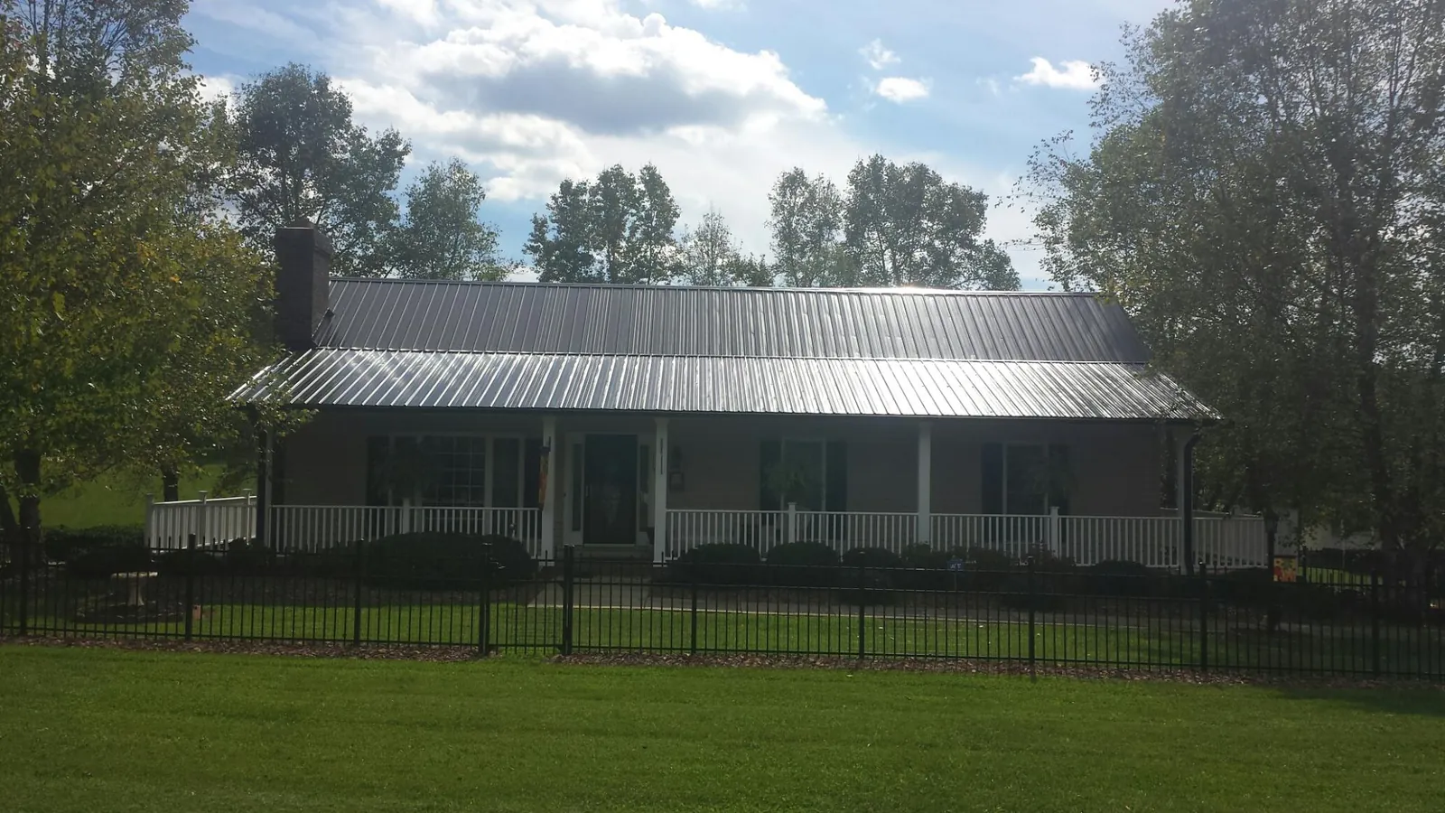 Gray metal roof on a brick ranch with a full width front porch — Gutter Guard Installation work by our crew in Athol